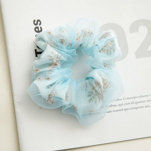 Close-up of light blue double-layer organza scrunchie with daisy floral patterns