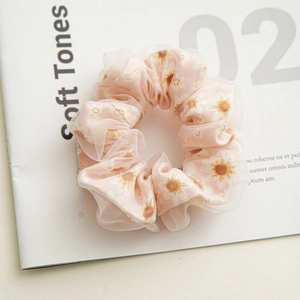 Detail of soft pink mesh scrunchie featuring white daisy prints and layered fabric