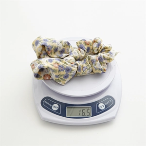 Detailed top view of a floral ponytail scrunchie on a scale weighing 16.5g