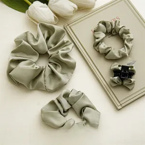 Détail de chouchous en satin vert sauge et pince à cheveux avec nœud et tulipes