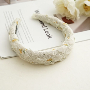 Gros plan du serre-tête floral avec motif de fleurs jaunes sur tissu texturé écru