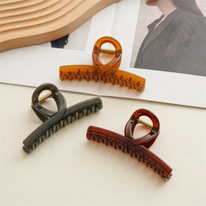 Close-up of three jelly colored resin hair claws on a decorative wooden tray