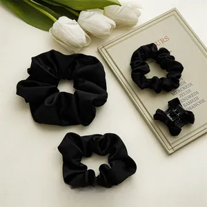 Vue détaillée du lot de chouchous en satin noir et pince à cheveux style minimaliste