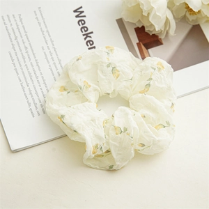 Vue détaillée du chouchou floral crème avec petites roses jaunes sur tissu texturé