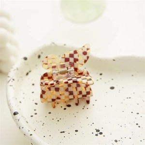 Détail de la pince à cheveux papillon avec motif damier marron et beige en acétate