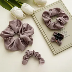 Détail d'un ensemble de chouchous en satin et pince à nœud dans un ton vieux rose élégant