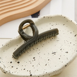 Macro detail of glossy dark green translucent hair claw clip with golden metal spring