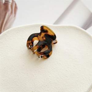Détail d'une pince à cheveux motif écaille de tortue sur un support blanc épuré