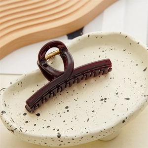 Deep burgundy translucent resin hair claw clip displayed on an elegant textured tray