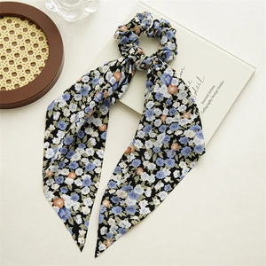 Close-up of black floral chiffon hair scrunchie with long ribbons on wooden tray