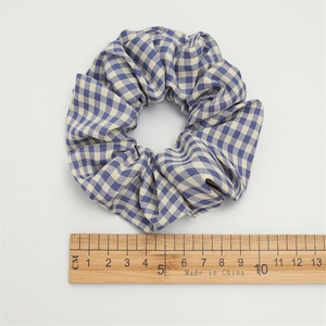 Detail view of blue and beige plaid fabric scrunchie next to a measuring ruler