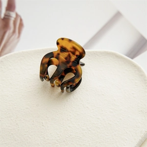 Détail de la pince à cheveux écaille de tortue sur support blanc au motif ambré