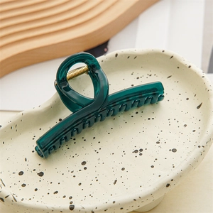 Close-up of translucent dark green jelly hair claw clip on aesthetic ceramic tray