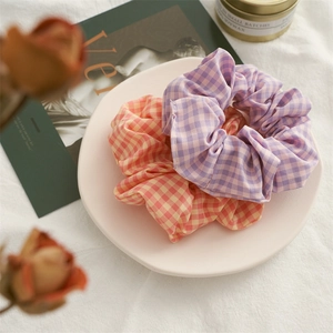 Detailed view of purple and orange plaid fabric scrunchies on a white decorative tray
