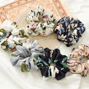 Set of six floral print fabric scrunchies in assorted colors on a woven mat