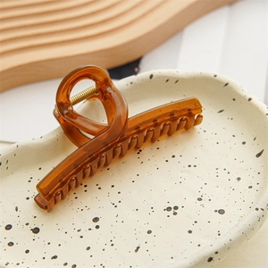 Detail view of amber jelly hair claw clip with cross design on white ceramic tray