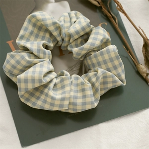 Detailed view of blue and yellow gingham scrunchie on vintage magazine background