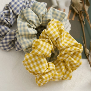 Three checkered hair scrunchies in blue green and yellow on a retro magazine background