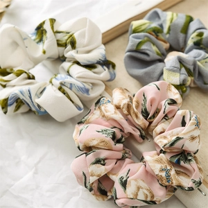 Detailed macro view of three floral printed scrunchies in pink, white and grey colors