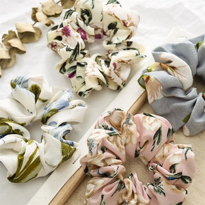 Close-up of assorted floral scrunchies in pastel pink, beige, and blue chiffon fabric