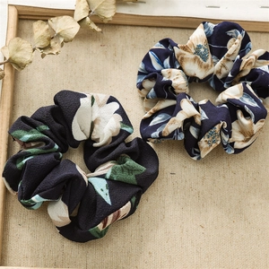Close-up of vintage floral scrunchies set on textured background with decorative dried plants
