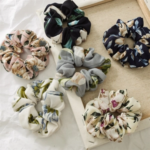 Set of six floral chiffon scrunchies in various colors arranged on a rustic wooden frame