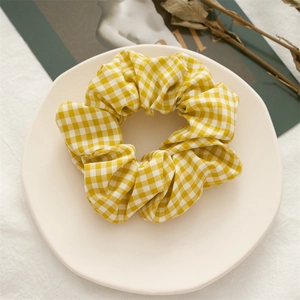 Close-up of yellow and white checkered fabric scrunchie on a ceramic display plate