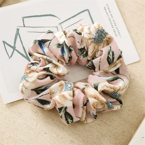 Close-up of pink floral satin scrunchie with vintage blossom pattern and soft texture