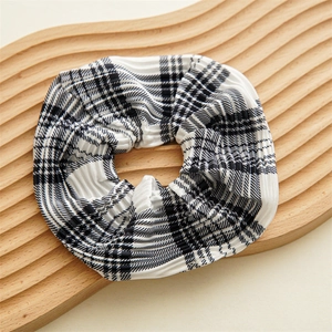 Detail shot of black and white checkered scrunchie with pleated plissé texture on wood