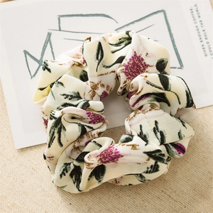 Detailed macro of floral print scrunchie showing cream fabric with pink blossom pattern