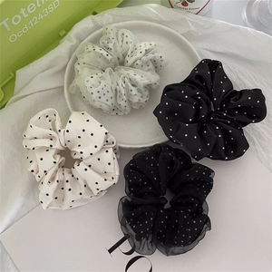 Dettaglio degli elastici scrunchie in raso e mesh a pois in classico nero e bianco
