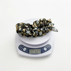 Gros plan sur le chouchou en mousseline florale pesant 12,7 grammes sur une balance