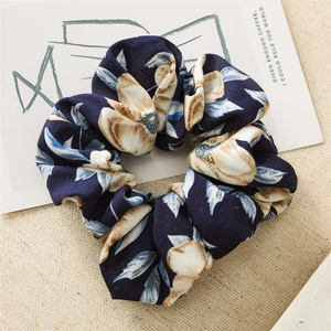 Detailed macro view of navy blue floral fabric scrunchie with white flower patterns