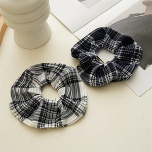 Detail of two plissé checkered hair scrunchies in black and white and navy blue