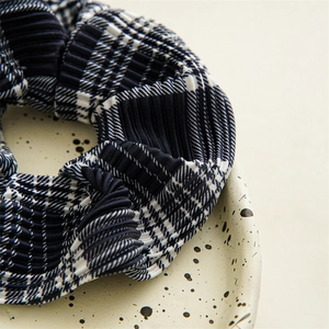 Detail of navy blue and white pleated checkered scrunchie on an artistic ceramic plate