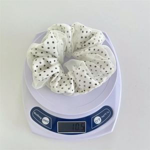 Dettaglio dello scrunchie in chiffon a pois con peso di 10,5 g mostrato sulla bilancia