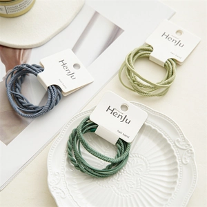 Elastic hair bands set in green and blue colors with braided texture on a ceramic plate