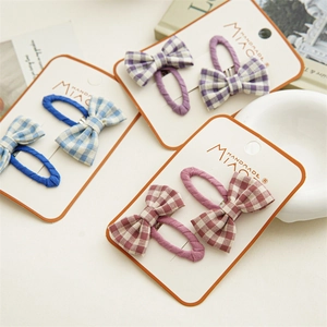 Detail of plaid bow hair clips in blue, purple, and burgundy on display cards