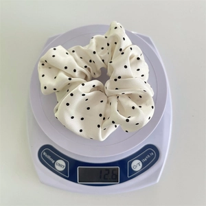 Vista ravvicinata dell'elastico in satin a pois da 12,6g su una bilancia per mostrare il peso