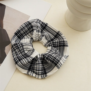 Detailed view of black and white checkered scrunchie with pleated fabric on magazine background