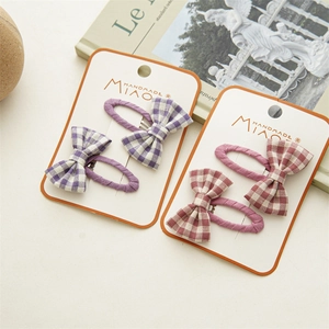 Detail of handmade plaid fabric bow hair clips in purple and burgundy on card