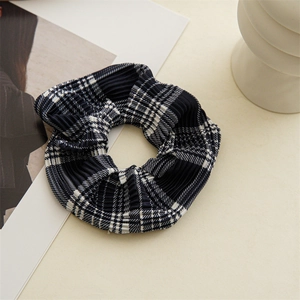 Close-up of a blue and white checkered scrunchie with detailed pleated fabric texture
