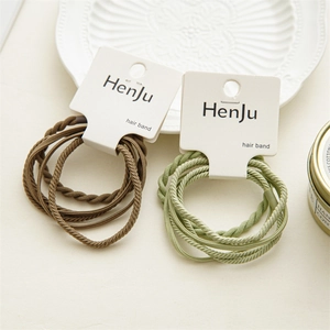 Detail of high-elastic braided hair bands in brown and light green on card packaging