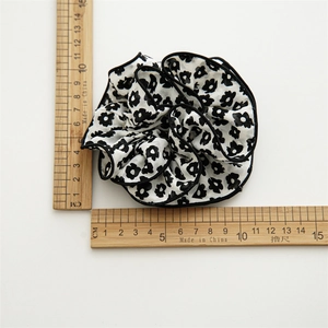 Floral chiffon scrunchie with black edging and white petal pattern, measuring 11cm