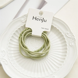 High-elastic sage green hair bands on a vintage white plate for styling and hair care