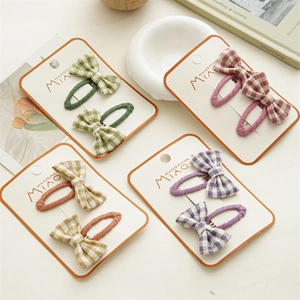 Detail view of plaid bow hair clips in multiple colors on a branded display card