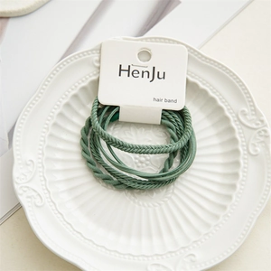 Detailed view of elastic hair bands in Morandi green displayed on a ceramic tray