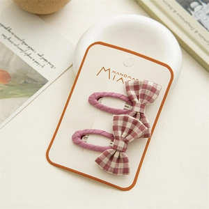 Detail of purple plaid bow hair clips on handmade display card with soft background