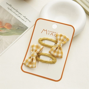 Detail of yellow and white checkered bow hair clips on handmade card with aesthetic decor