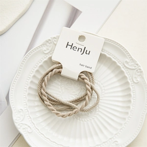 Detailed view of elastic braided hair bands in light beige on a branded display card
